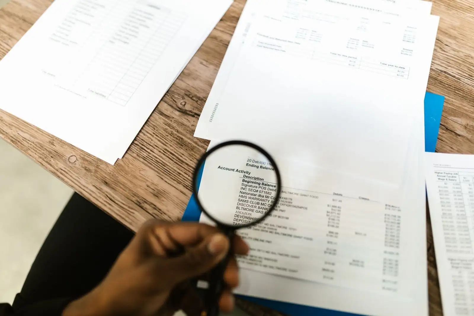 Loupe tenue au-dessus d'un relevé imprimé, pour vérifier une information ligne par ligne