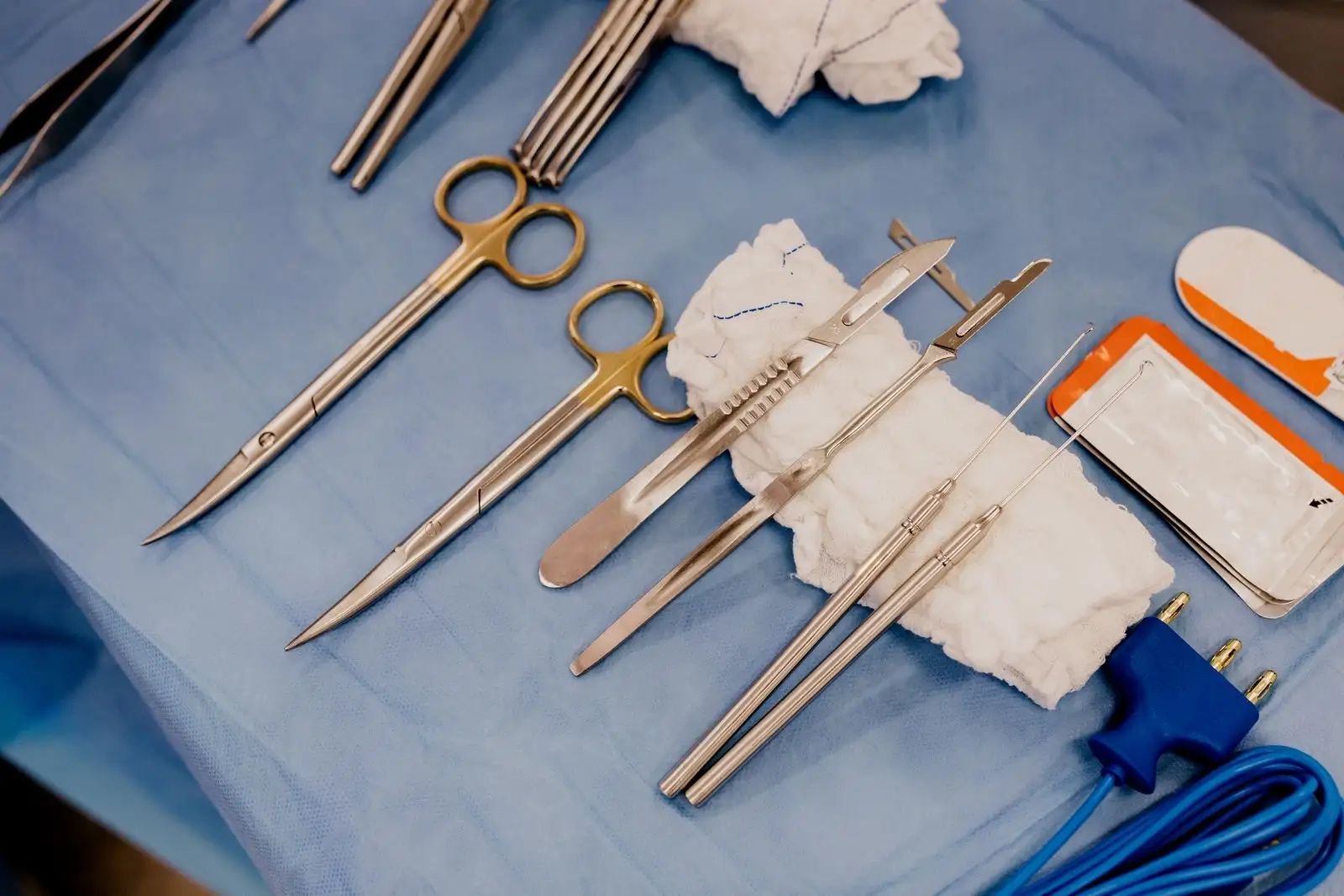 Instruments chirurgicaux stériles alignés sur un champ bleu en salle d'opération