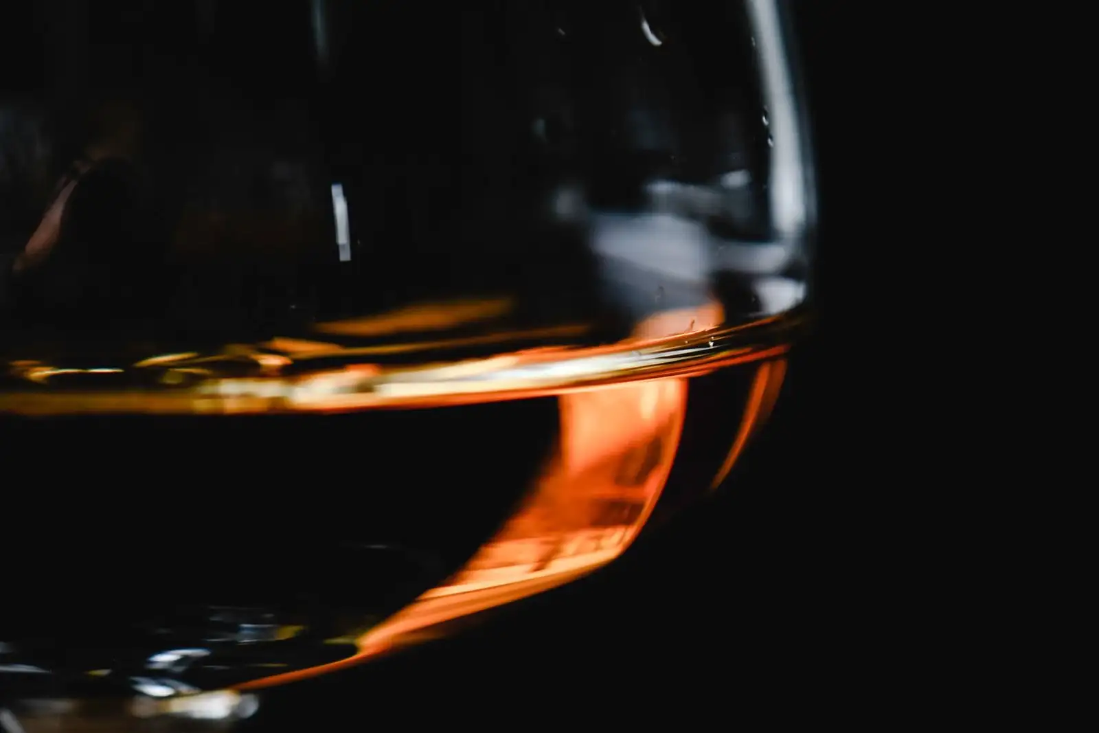 Verre à cognac en gros plan, un fond d'alcool ambré éclairé sur fond noir