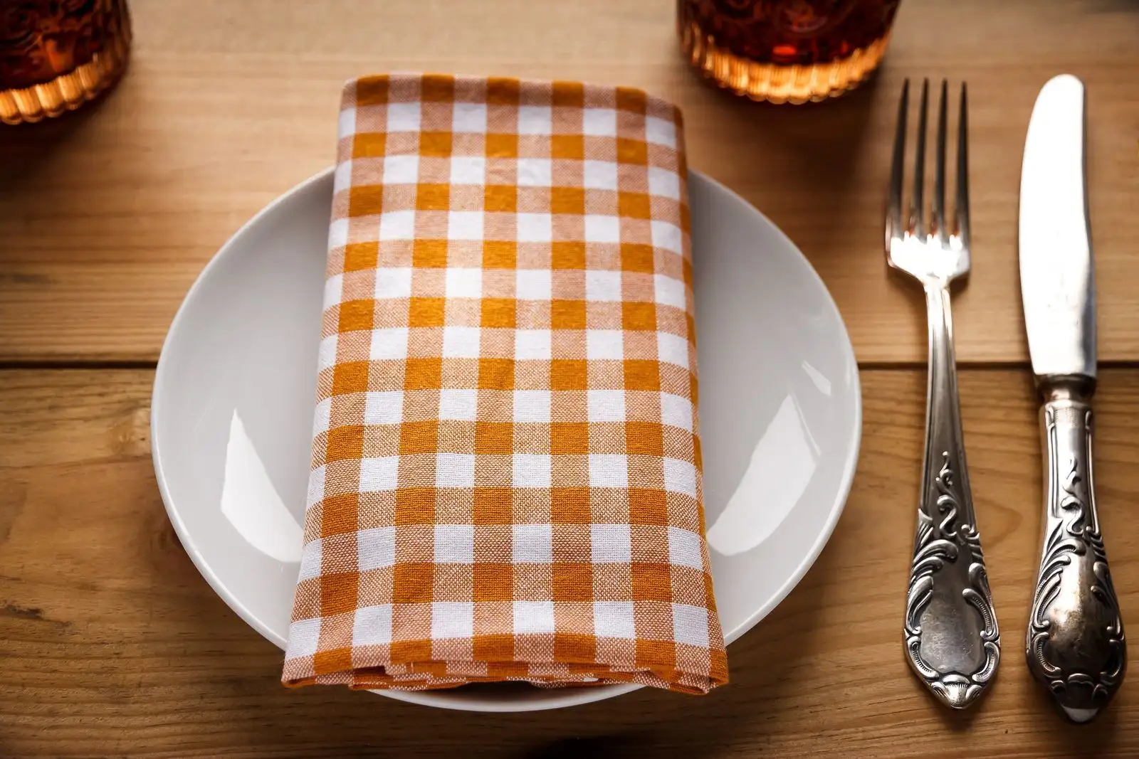 Assiette vide avec serviette à carreaux, fourchette et couteau posés sur une table en bois