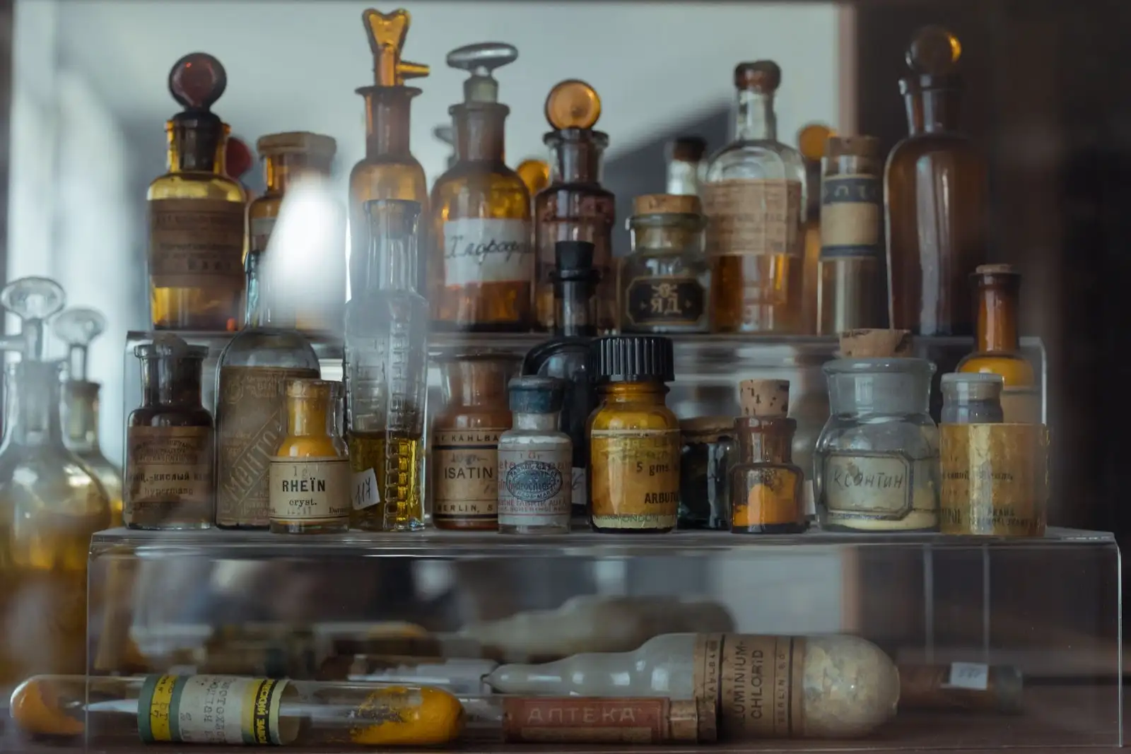Anciens flacons de pharmacie en verre ambré et transparent, étiquetés, alignés sur une étagère