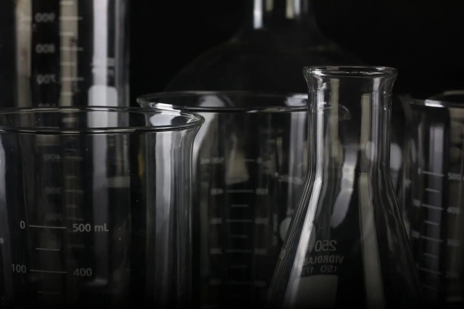 Béchers, fiole d'Erlenmeyer et éprouvettes graduées en verre sur fond noir