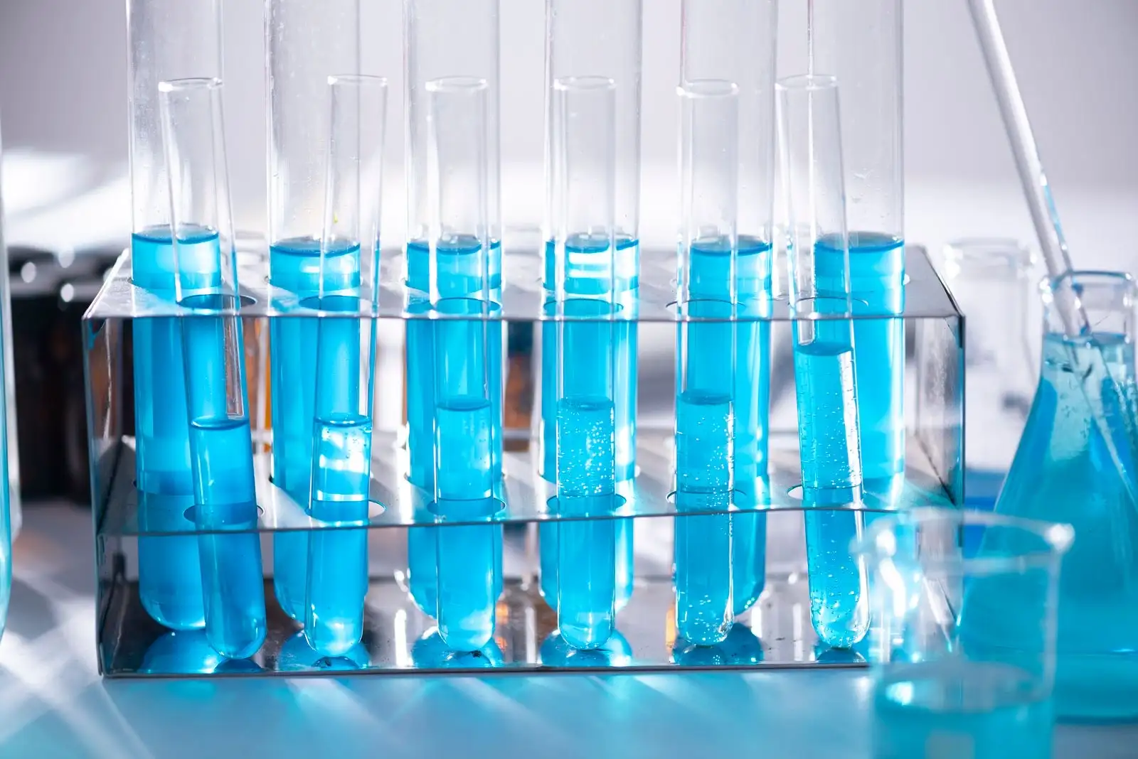 Tubes à essai remplis d'un liquide bleu alignés sur un portoir de laboratoire