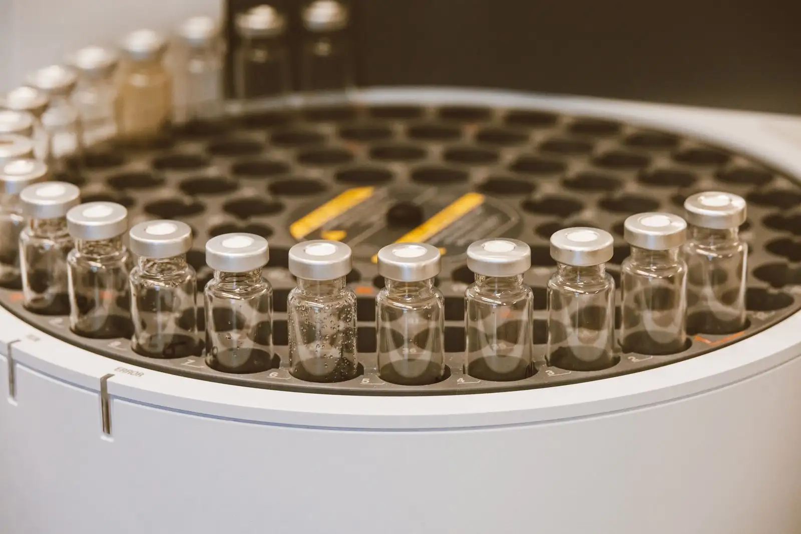 Flacons d'échantillons en verre alignés sur le plateau d'un passeur automatique de chromatographe