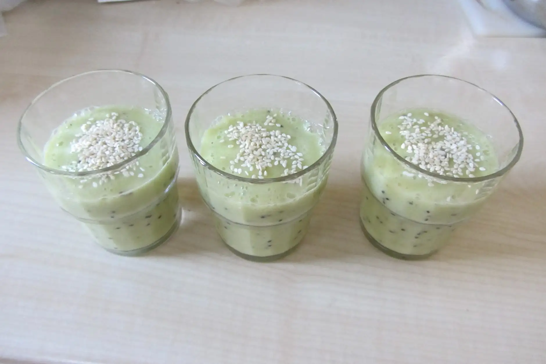 Trois verres de smoothie vert pâle alignés.