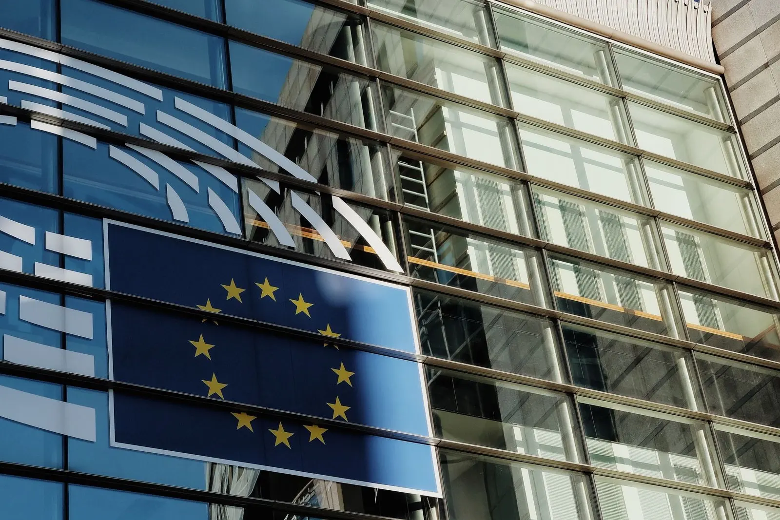 Façade vitrée d'un bâtiment des institutions européennes à Bruxelles, avec le drapeau de l'Union européenne