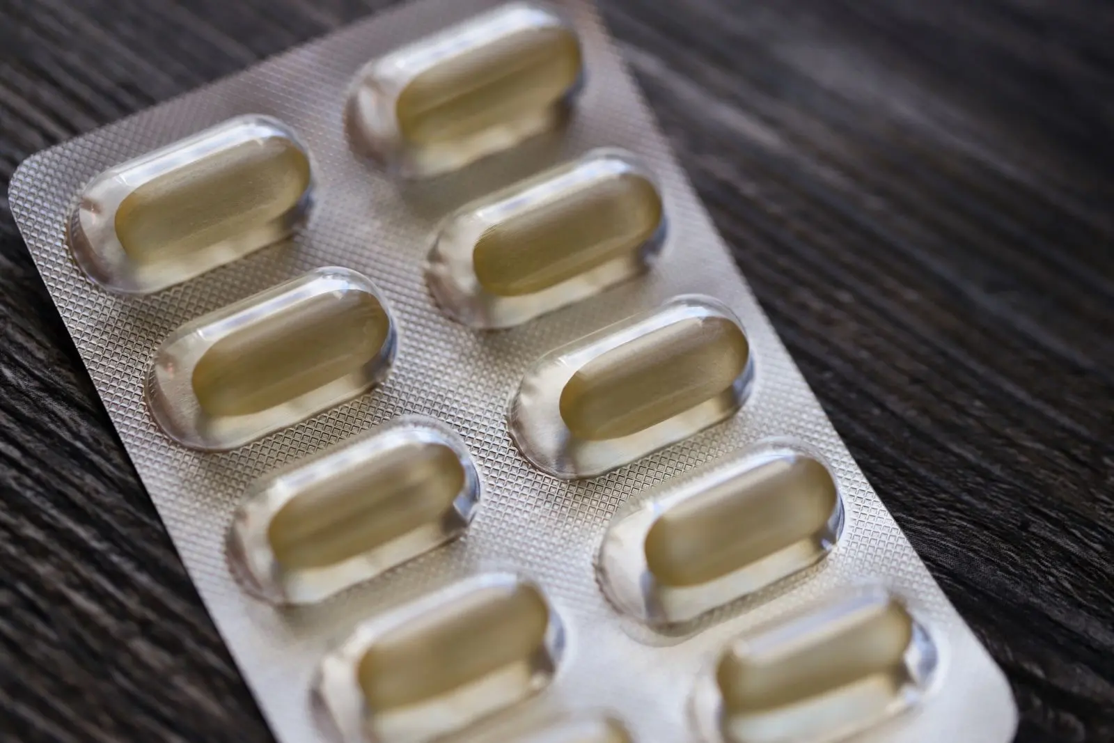 Plaquette de gélules sur une table en bois, un médicament parmi ceux dont le CBD peut modifier l'élimination