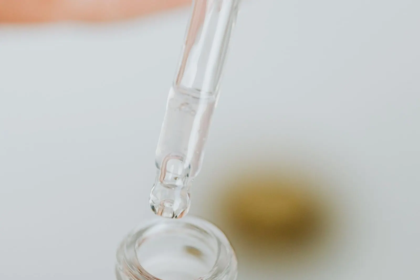 Pipette de verre au-dessus d'un flacon ouvert, une goutte prête à tomber