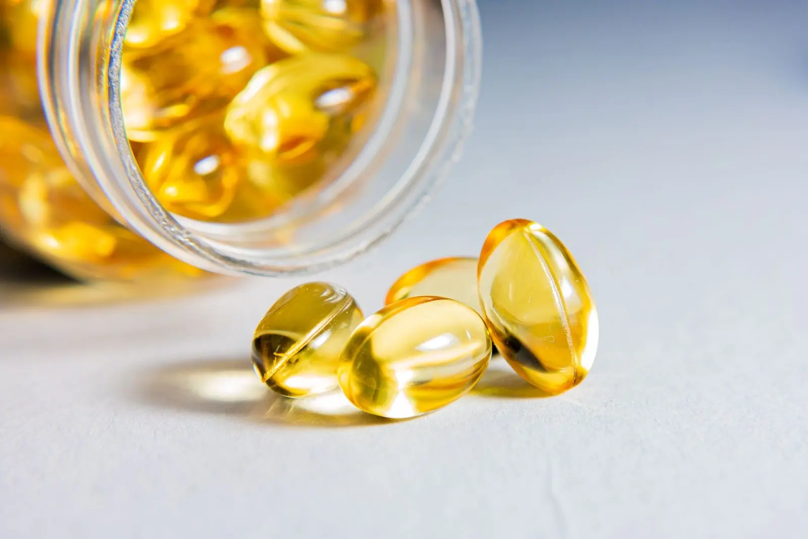 Capsules molles transparentes remplies d'huile, échappées d'un flacon en verre