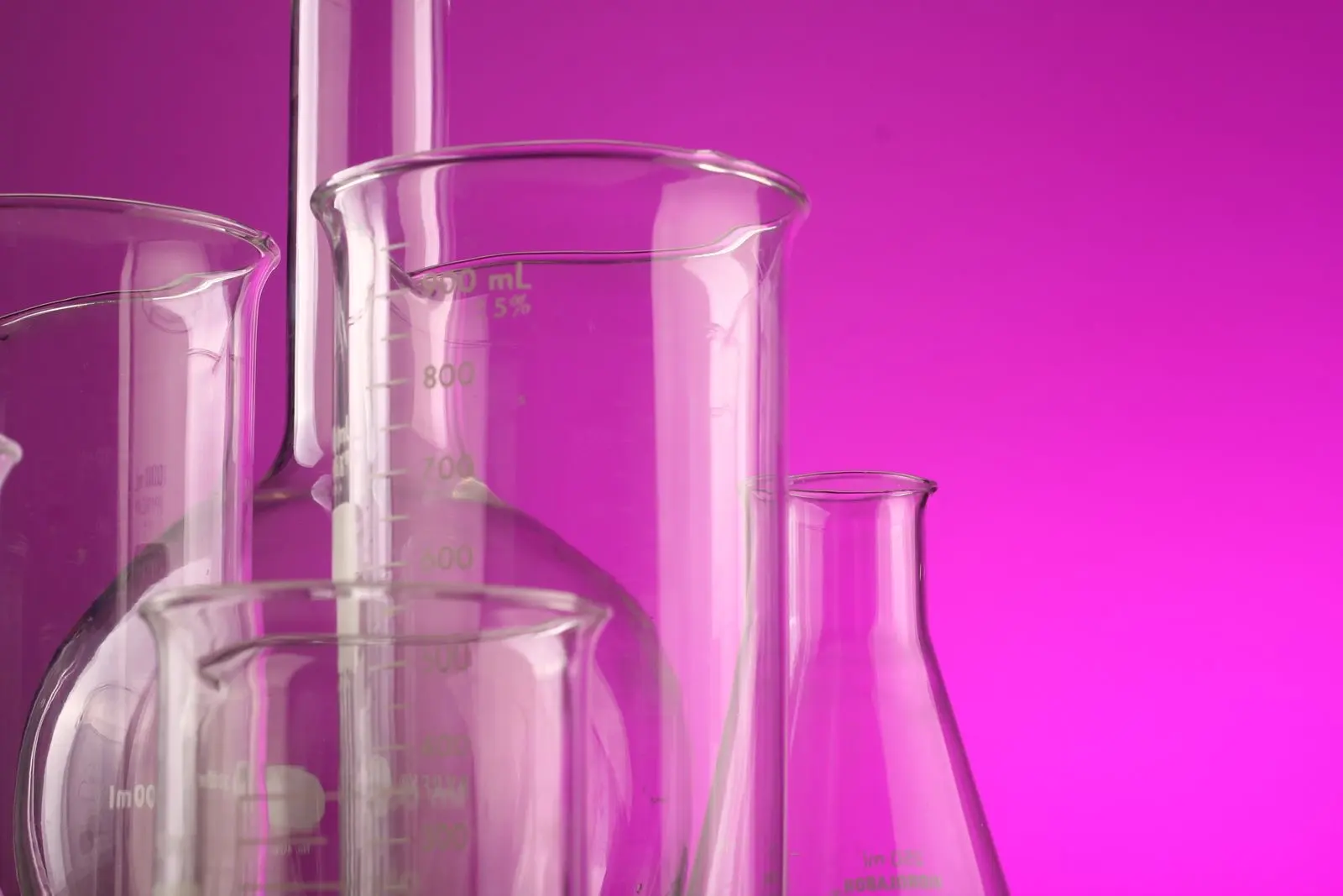 Verrerie de laboratoire graduée, fioles et béchers vides sur fond magenta
