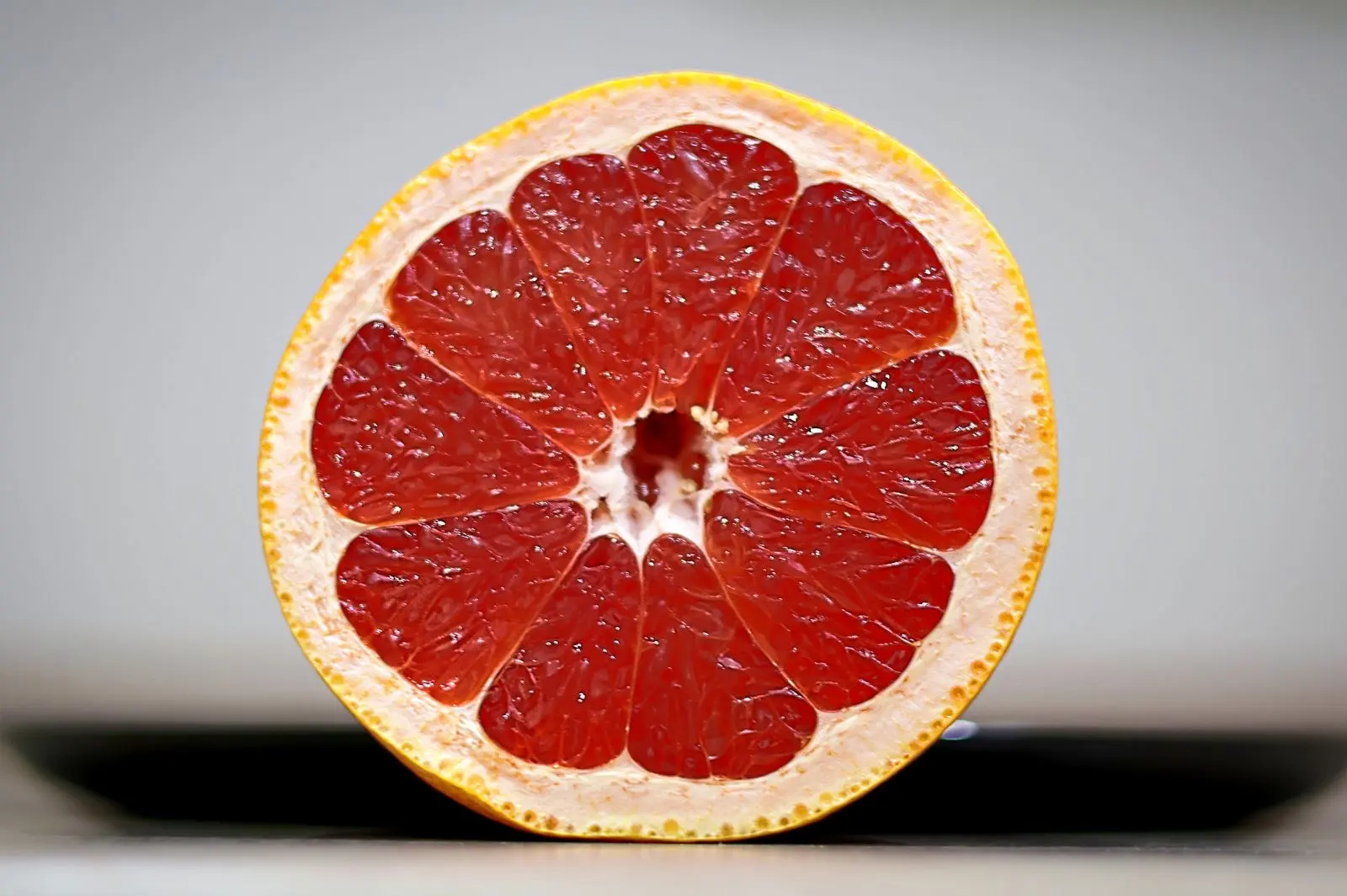 Demi-pamplemousse rose coupé en gros plan, le fruit dont les interactions avec les médicaments sont les plus étudiées