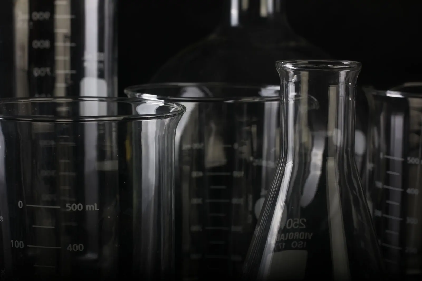 Béchers, fiole d'Erlenmeyer et éprouvettes graduées en verre sur fond noir