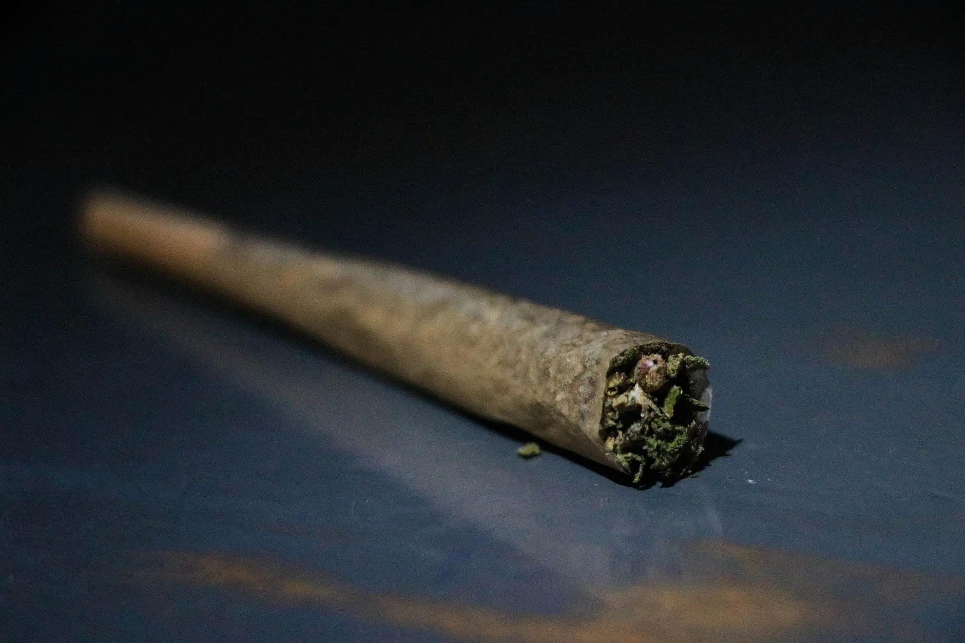 Joint roulé posé sur une surface bleue, en gros plan ; photo d'illustration.